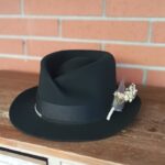 Black felt fedora with architectural crown and white preserved flower detail