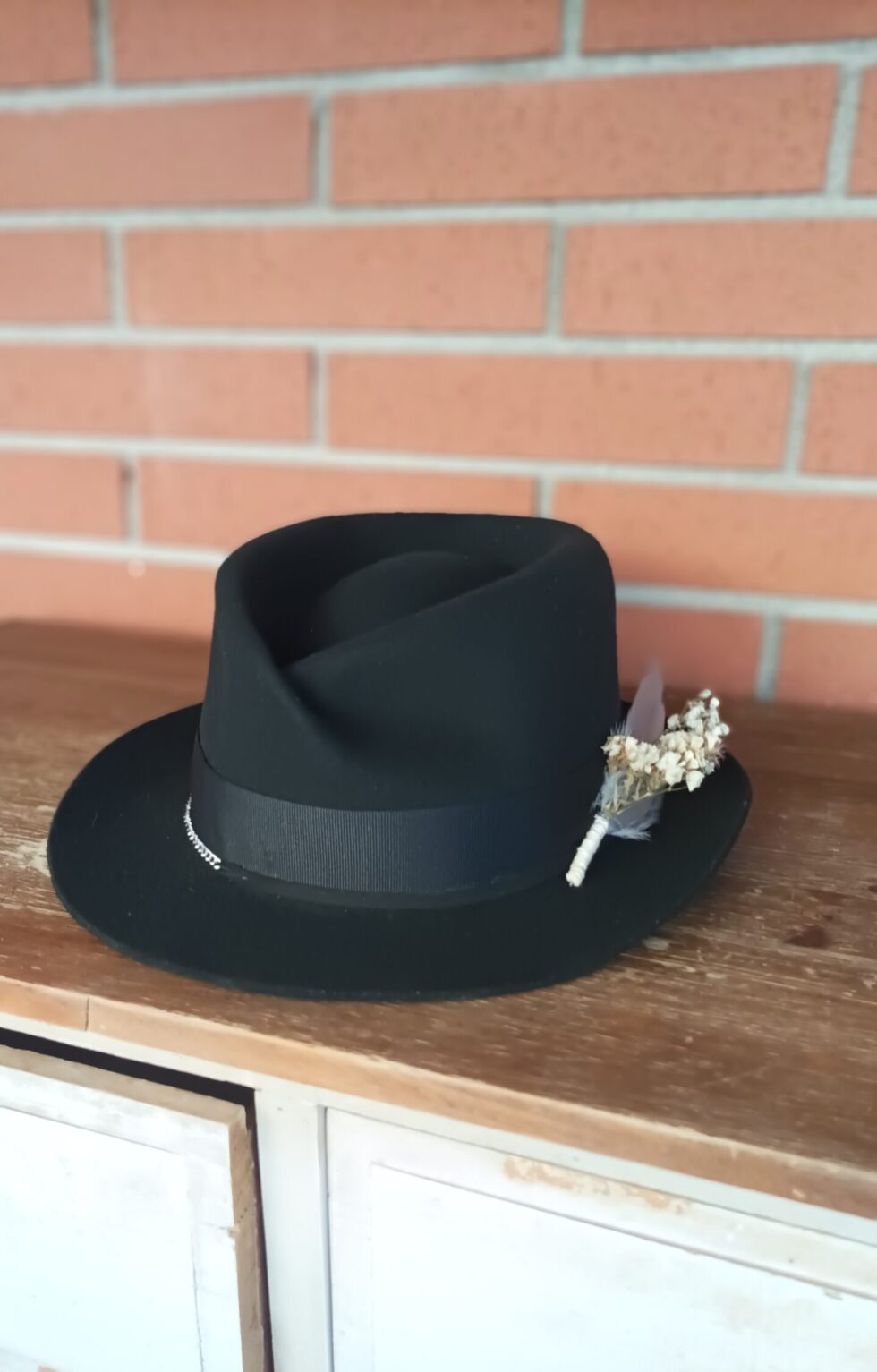Black felt fedora with architectural crown and white preserved flower detail
