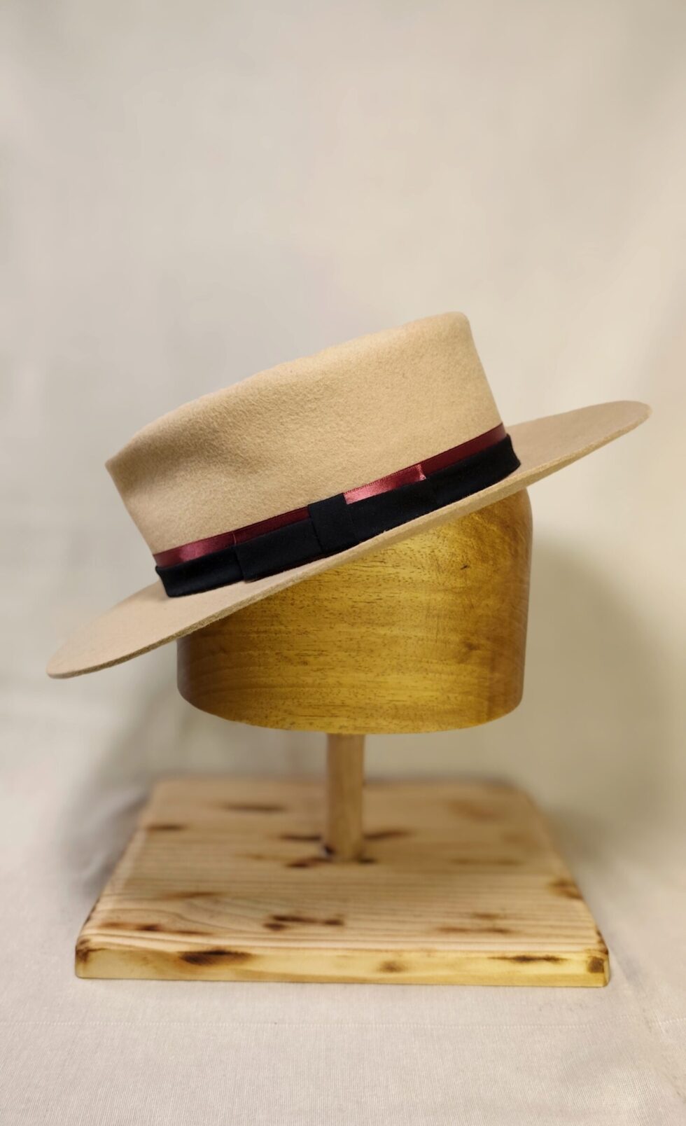 Hand-blocked sand wool felt hat with dual-tone black and burgundy grosgrain ribbon.